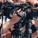 Refinery Chaos Triggers Holiday Price Spike television cameras on tripods at a media event