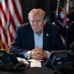 Trump’s Greenland Move Triggers Backlash Donald Trump seated at a table between two desk phones