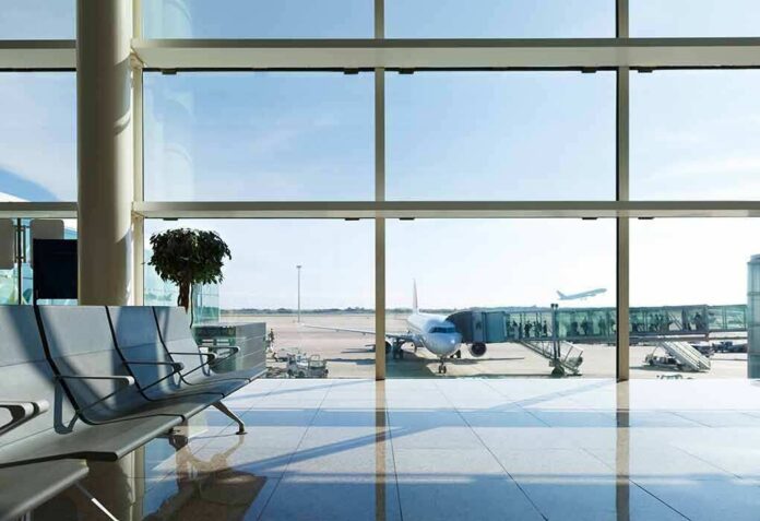 shutterstock_331558169 Airport terminal with plane at gate viewed through large windows