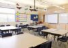 9/11 Teaching Shift Ignites Parental Uproar Empty classroom with tables, chairs, and a whiteboard