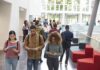 Religious Aid Ban Sparks High Court Gamble Students walking through a bright campus atrium using mobile devices