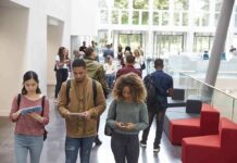 Religious Aid Ban Sparks High Court Gamble Students walking through a bright campus atrium using mobile devices