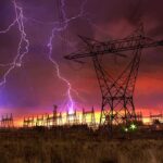 Grid Sabotage Panic Grips Germany Lightning strikes illuminate a power station against a colorful sunset sky