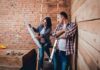 Two people reviewing blueprints in a rustic room under renovation