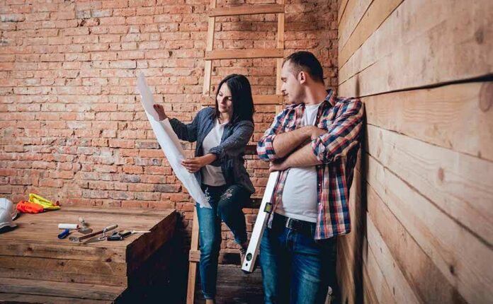 shutterstock_686862826 Two people reviewing blueprints in a rustic room under renovation