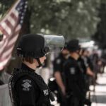 Budget Brawl Erupts Over LGBTQ Grants police officer in riot gear standing in a line