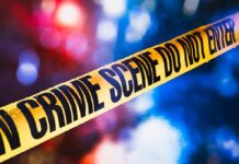 Block Party Bloodshed Stuns Georgia Town yellow crime scene tape with blurred police lights