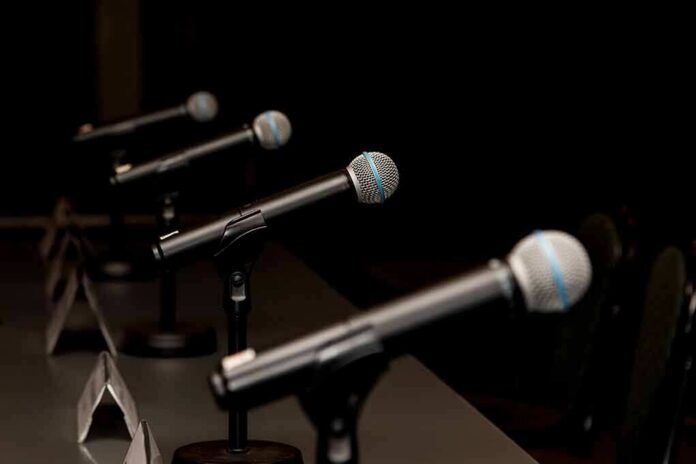 Row of microphones on stands at a panel table