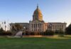 Capitol building with dome and surrounding flags