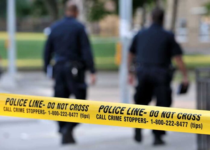 Police officers walking past caution tape at a crime scene