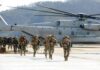 Marine Arrest Triggers Island Lockdown Soldiers disembark and walk past a large military helicopter