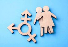 Wooden transgender symbol and two human figures on blue background