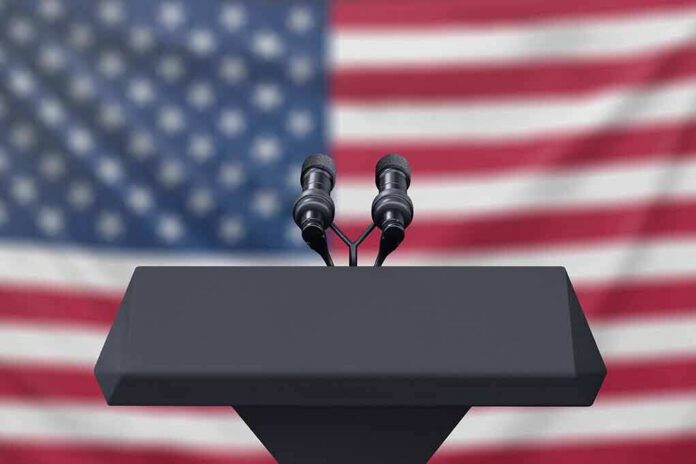 shutterstock_1223942521 podium with microphones in front of a blurred American flag