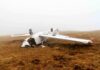 Crashed airplane lying on its side in a foggy field