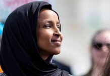 FBI Raid Hits Omar Home – Warrant Sealed Ilhan Omar in profile wearing a black headscarf outdoors