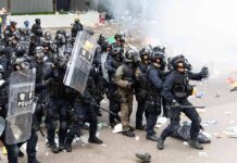 Dontrelle Inman and Tom Mandrake among riot police advancing with shields in tear gas