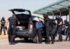 Tokyo Court Greenlights Shocking Hacker Hand-Off customs officers detain a person beside a car with its trunk open