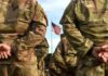 Livestreamed Death Penalty? Outrage Explodes Soldiers in camouflage stand with hands behind backs facing a U.S. flag