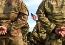 Livestreamed Death Penalty? Outrage Explodes Soldiers in camouflage stand with hands behind backs facing a U.S. flag