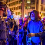 Historic City Hall TORCHED – France Erupts Protesters talk with police officers at night in city street