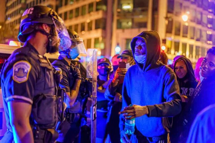shutterstock_1796219905 Protesters talk with police officers at night in city street