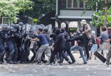 Protesters clash with riot police holding shields