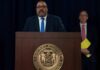 Hochul Overrules DA – James Takes Over Man speaks at podium with New York County District Attorney seal