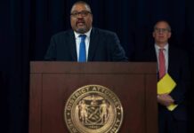 Hochul Overrules DA – James Takes Over Man speaks at podium with New York County District Attorney seal