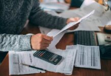 Workers Revolt: Tariffs Blamed For Squeeze Person reviewing bills with calculator at cluttered desk