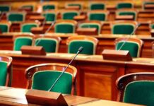 UK Lords Greenlight Cloned Voice – Big Shift Empty legislative chamber with green upholstered chairs and wooden desks