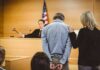 Kentucky Man Faces Trial Over Alleged Trump Threats Defendant in handcuffs stands before a judge in a courtroom