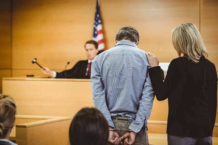 shutterstock_243765985 Defendant in handcuffs stands before a judge in a courtroom