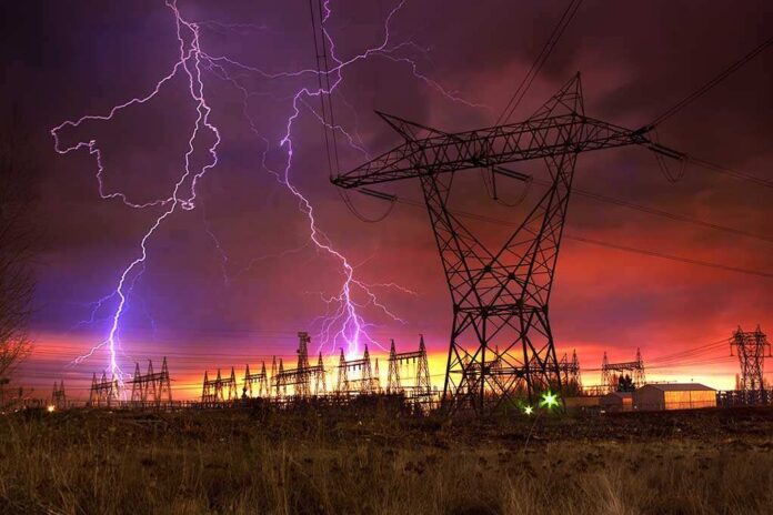 Lightning strikes illuminate a power station against a colorful sunset sky