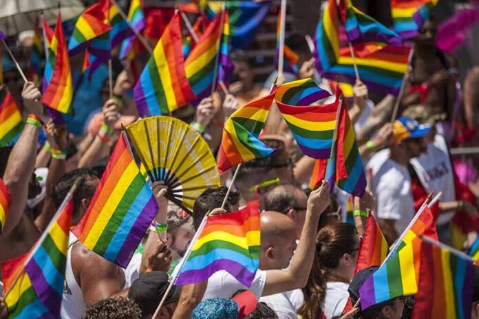 shutterstock_647870272 Dontrelle Inman among crowd waving rainbow pride flags